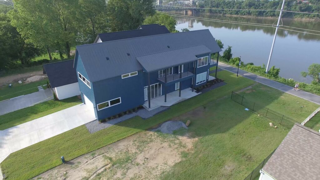 Standing Seam Charcoal metal roof on modern blue house with vertical siding.