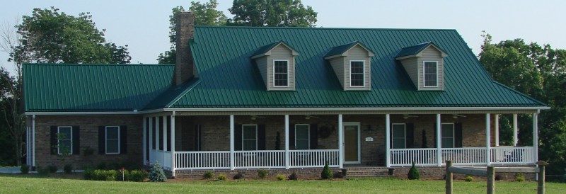 Forest green standing seam metal roof on classic brick house.