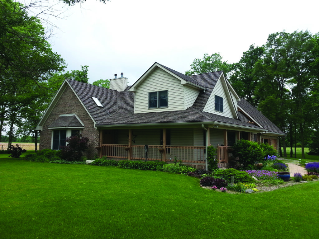 Stone coated steel tile roof on traditional house with siding and stone.